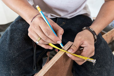 Midsection of man marking on wood in workshop