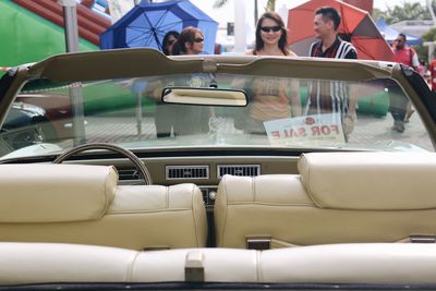 People standing in front of convertible car for sale