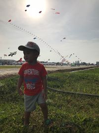 Full length of boy standing on field against sky