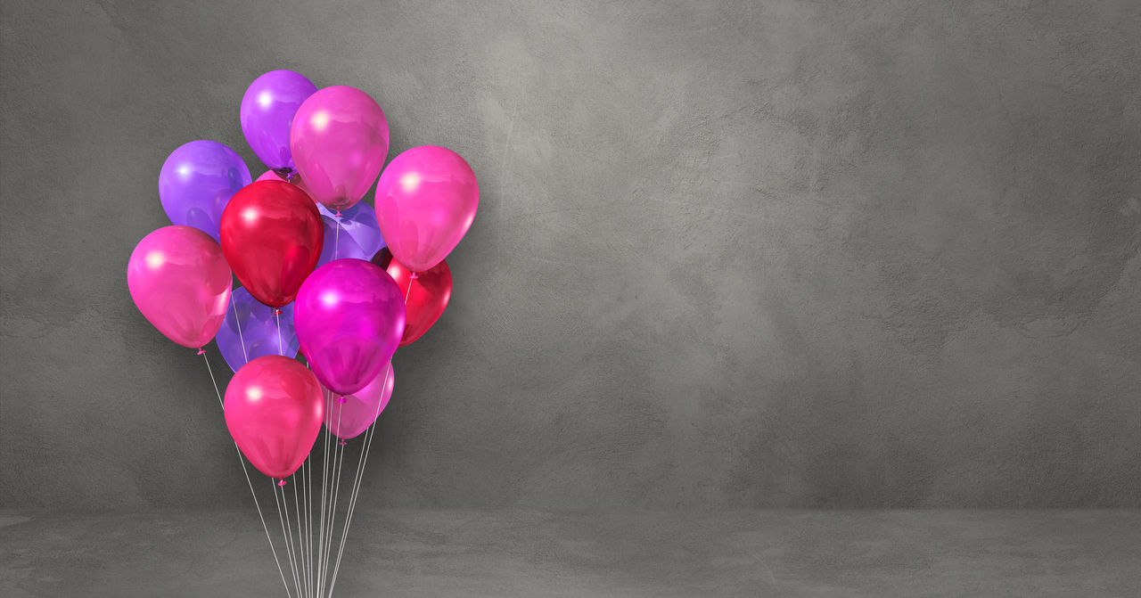 MULTI COLORED BALLOONS AGAINST PINK WALL