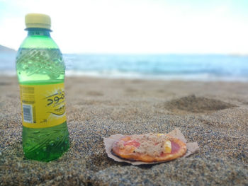 Close-up of drink on table at beach against sky