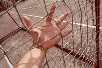 Close-up of hand holding sports net