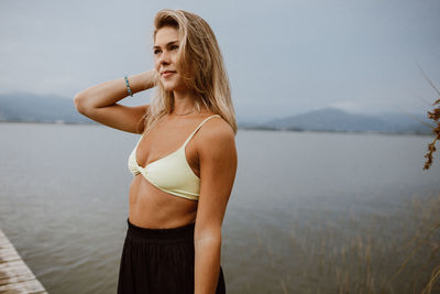 Portrait of young woman standing against sky