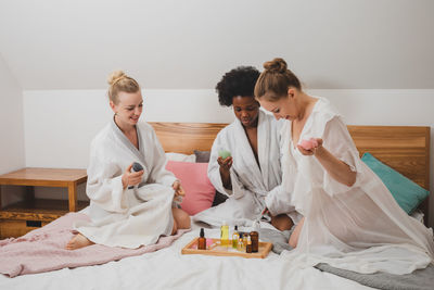 Female friends sitting on bed at home