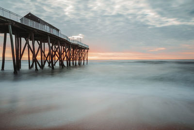 Pier over sea against sky during sunset