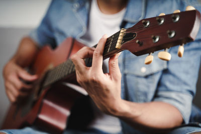 Midsection of man playing guitar