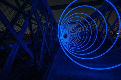 Illuminated blue spiral of bridge at night