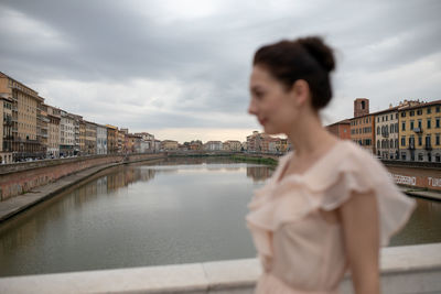 Side view of woman standing against river in city