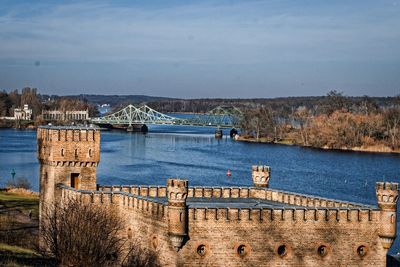 Arch bridge over river against sky in city