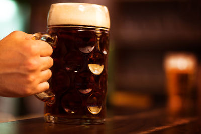 Close-up of hand holding beer glass on table