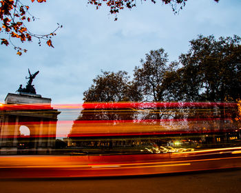 Red light trails in city against sky