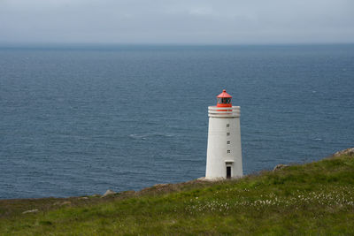 Lighthouse by sea against sky