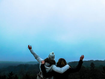 Woman with arms raised against clear sky