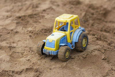 Children's toy tractor on the sandbox.a forgotten toy.