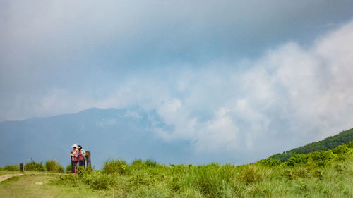 Rear view of women walking on the mountain against sky