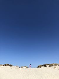 Woman on shore against clear blue sky