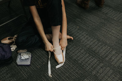 Overhead shot of girl putting on ballet point shoe