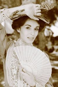 Portrait of beautiful young woman holding folding fan