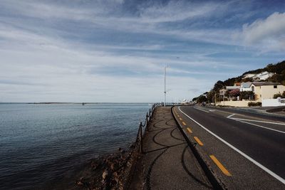 Coastal road by sea against sky