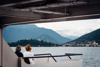 Rear view of people looking at lake against mountains