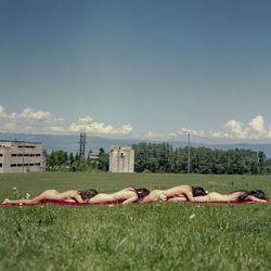 Woman sleeping on grass against sky