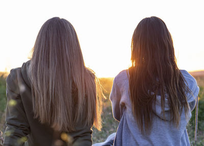 Two girls back to back watching the sunset person