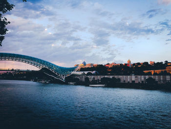 Bridge over river against cloudy sky