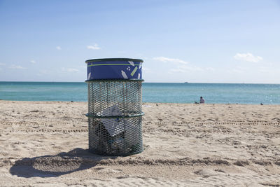 Trashcan on a beach against sky