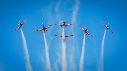Low angle view of airshow against blue sky