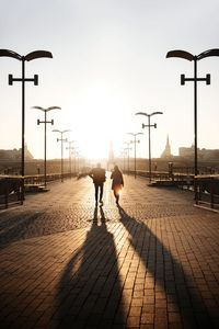 Rear view of people walking on street against sky