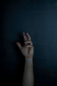 Cropped hand of man against black background