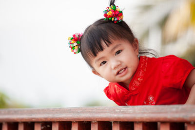 Portrait of cute baby girl standing at railing