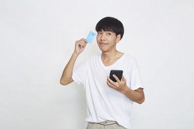 Young man using mobile phone against white background