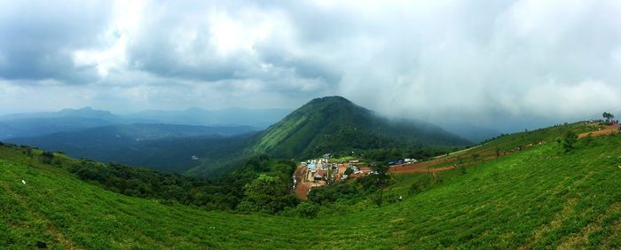 Panoramic view of agricultural field and houses against sky