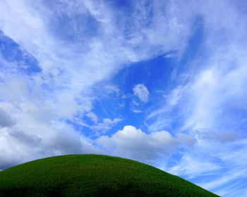 Low angle view of green landscape against sky