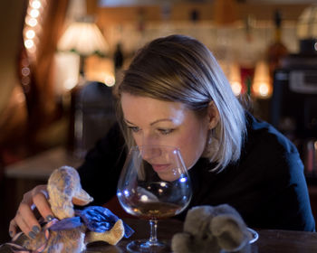 Close-up of mid adult woman holding toys by wineglass on restaurant table