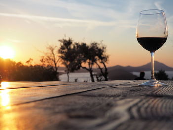 Close-up of wineglass on table against sky during sunset