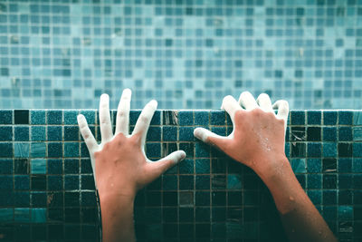 Cropped image of person hand with wall in swimming pool