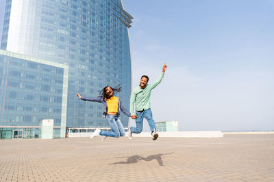Young couple jumping against building