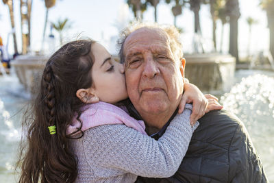 Close-up of granddaughter kissing grandfather outdoors