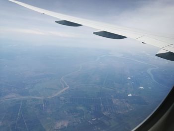 Aerial view of aircraft wing over landscape against sky