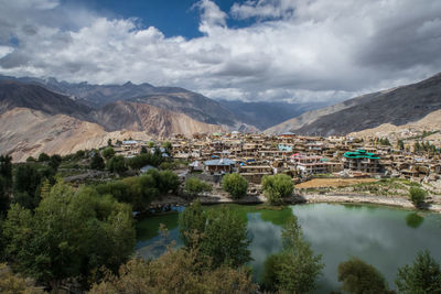 High angle view of houses amidst mountains against cloudy sky