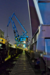Train at illuminated railroad station against blue sky