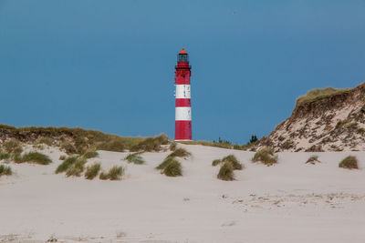 Lighthouse on street amidst buildings against sky