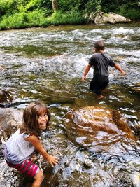 Siblings wading in river