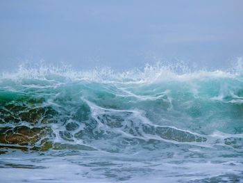 Waves splashing in sea against sky
