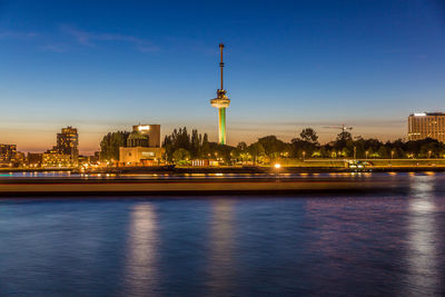 Night cityscape of the new maas river, illuminated buildings by the river against blue sky, euromast