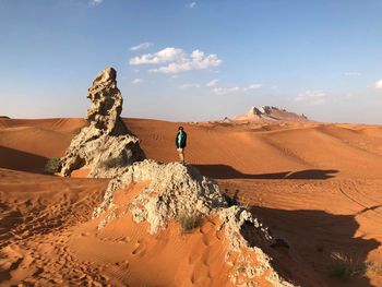 Smiling young woman standing on rock at desert