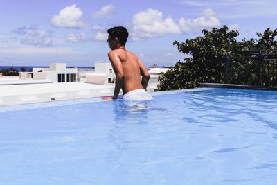 Rear view of shirtless man in swimming pool