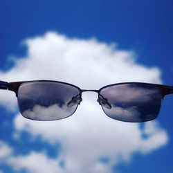 Low angle view of sunglasses against cloudy sky